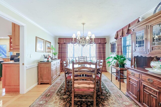 dining space with ornamental molding, a chandelier, light wood-style floors, and baseboards