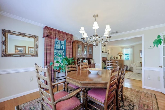 dining area featuring an inviting chandelier, ornamental molding, and wood finished floors