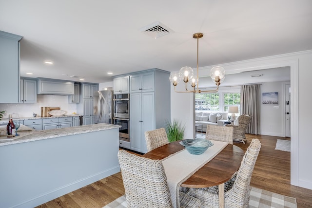 dining area with a chandelier, wood finished floors, recessed lighting, baseboards, and crown molding