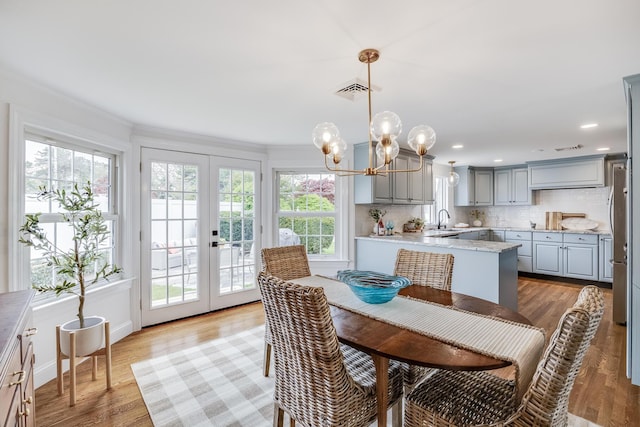 dining area with healthy amount of natural light, french doors, a chandelier, recessed lighting, and ornamental molding