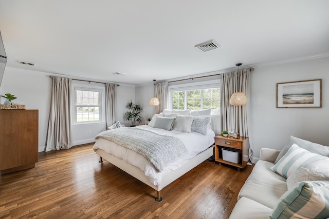 bedroom with multiple windows, crown molding, wood finished floors, and baseboards
