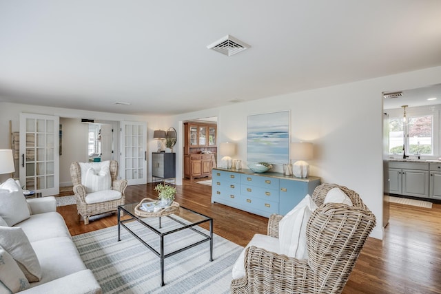 living area featuring plenty of natural light, french doors, wood finished floors, and baseboards