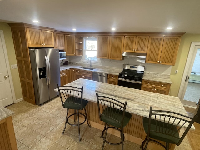 kitchen with stainless steel appliances, light stone countertops, sink, and a breakfast bar area