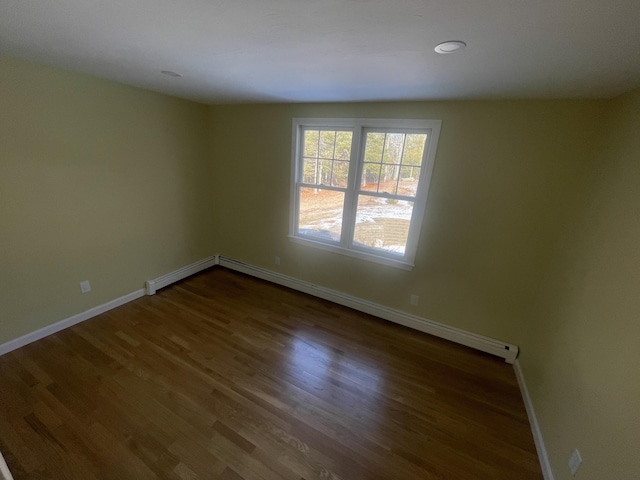 unfurnished room with dark hardwood / wood-style floors and a baseboard heating unit