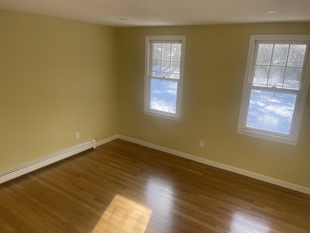 spare room featuring a baseboard radiator, hardwood / wood-style floors, and a wealth of natural light