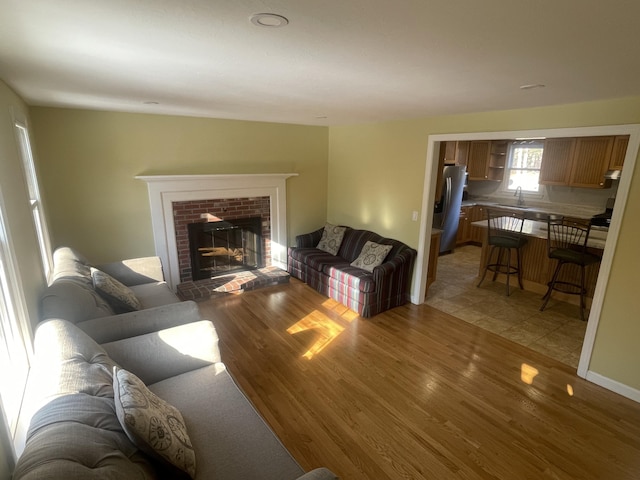 living room featuring sink, light hardwood / wood-style flooring, and a fireplace