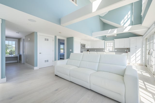 living room with light wood-type flooring and a high ceiling