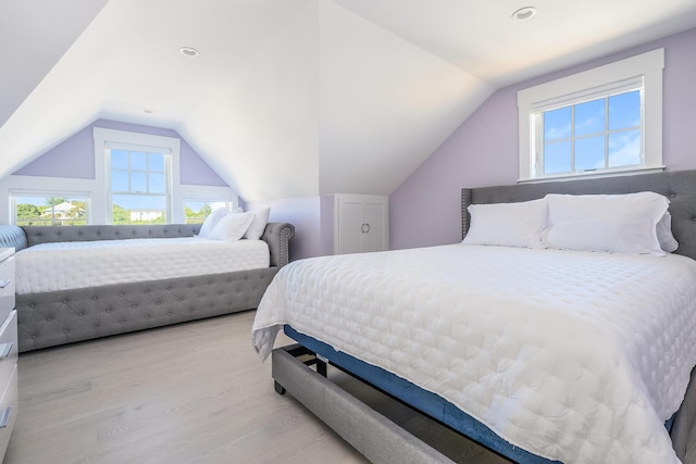 bedroom featuring multiple windows, light hardwood / wood-style flooring, and lofted ceiling