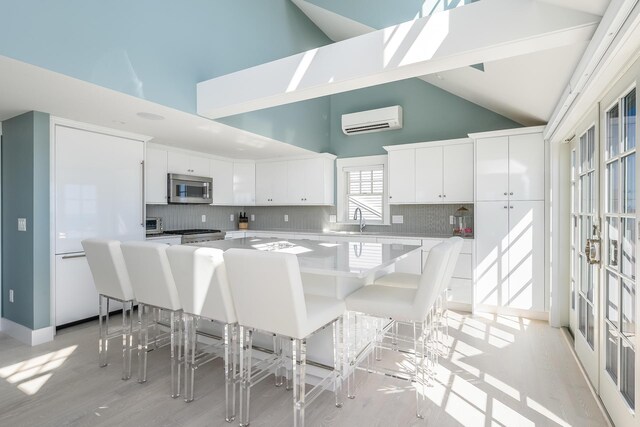 kitchen featuring white cabinetry, high vaulted ceiling, tasteful backsplash, and a kitchen breakfast bar