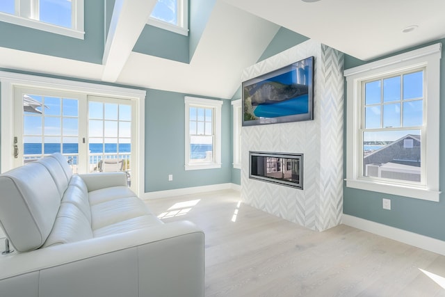 living room featuring vaulted ceiling, light hardwood / wood-style flooring, and a tile fireplace