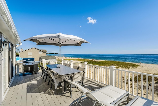 wooden terrace featuring a grill, a water view, and a view of the beach