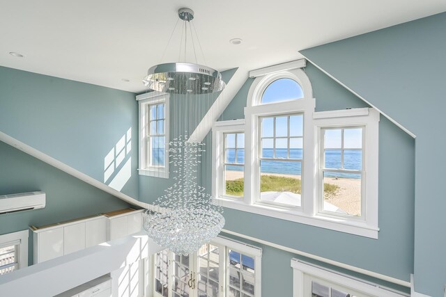 room details featuring a notable chandelier, a water view, an AC wall unit, and a beach view