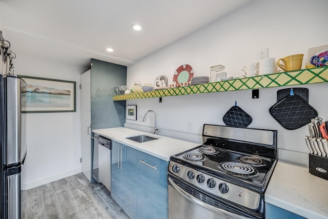 kitchen with appliances with stainless steel finishes, a sink, blue cabinetry, light wood-style floors, and open shelves