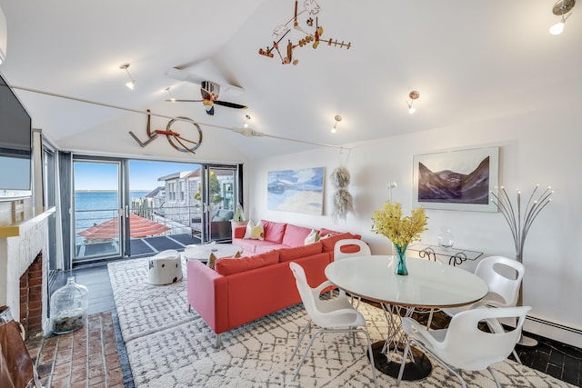living area featuring lofted ceiling, a fireplace, a water view, and ceiling fan