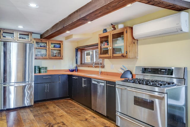 kitchen featuring stainless steel appliances, a sink, an AC wall unit, recessed lighting, and beam ceiling