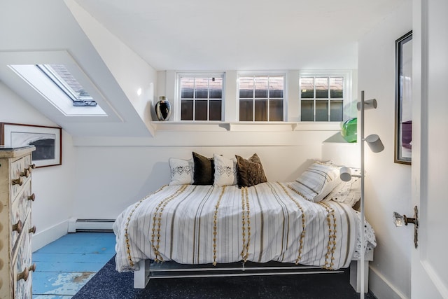 bedroom with a skylight, a baseboard radiator, and baseboards