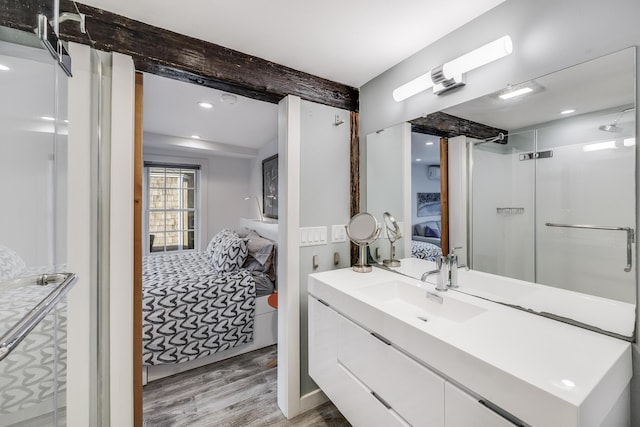 ensuite bathroom with wood finished floors, beamed ceiling, vanity, recessed lighting, and an enclosed shower