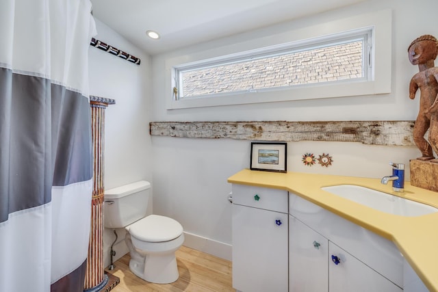 bathroom featuring toilet, wood finished floors, vanity, baseboards, and curtained shower