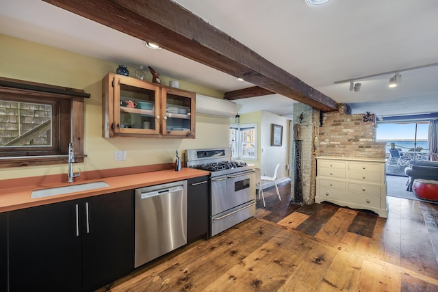 kitchen with stainless steel appliances, a sink, dark wood finished floors, light countertops, and beamed ceiling