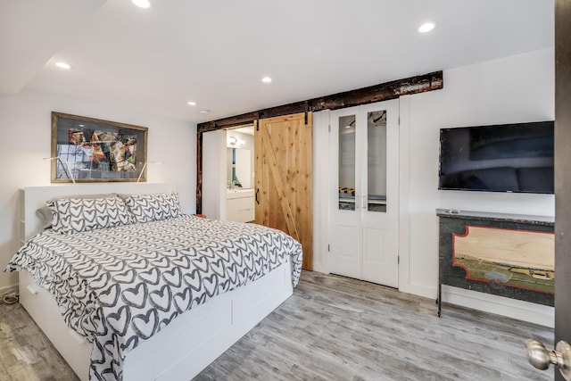 bedroom featuring a barn door, wood finished floors, and recessed lighting