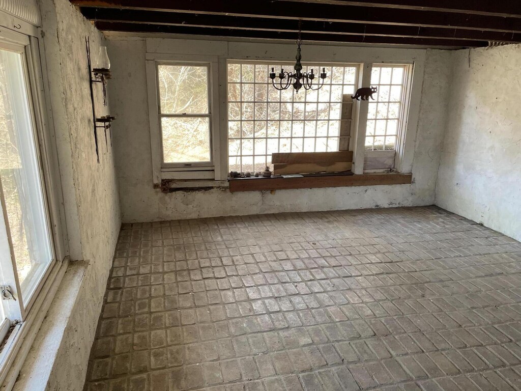 15 Cabral Farm Rd, Truro, MA 02666 - unfurnished dining area featuring brick floor, an inviting chandelier, and plenty of natural light