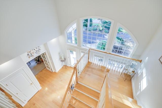 stairs with hardwood / wood-style flooring and a towering ceiling