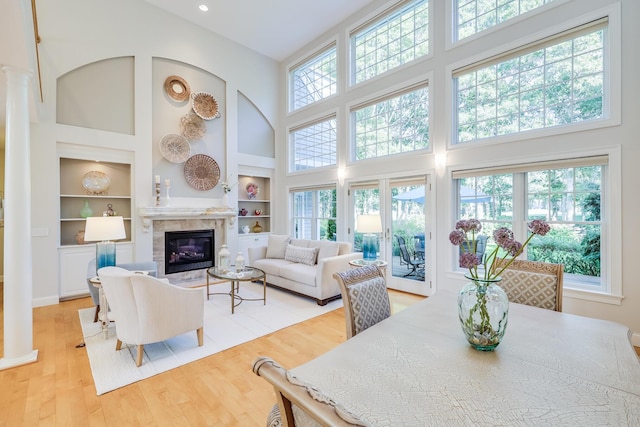 living room with a healthy amount of sunlight, a towering ceiling, light hardwood / wood-style flooring, and built in shelves