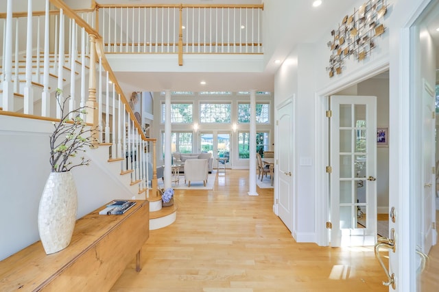 foyer entrance with a towering ceiling and light hardwood / wood-style flooring