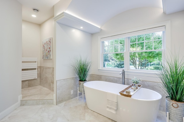 bathroom featuring tile walls and a tub to relax in