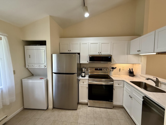 40 Eaton Ln, Brewster, MA 02631 - kitchen featuring stainless steel appliances, stacked washer / dryer, a sink, vaulted ceiling, and backsplash