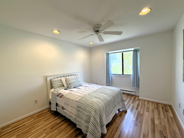 bedroom featuring baseboard heating, wood finished floors, baseboards, a ceiling fan, and recessed lighting