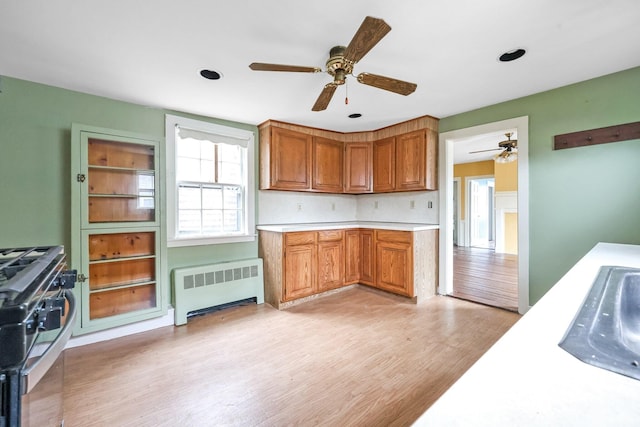 32 Church St, Sandwich, MA 02563 - kitchen featuring radiator heating unit, stainless steel gas range oven, a ceiling fan, light countertops, and light wood finished floors