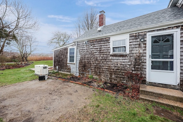 32 Church St, Sandwich, MA 02563 - view of side of home featuring a chimney, a patio, roof with shingles, a yard, and entry steps