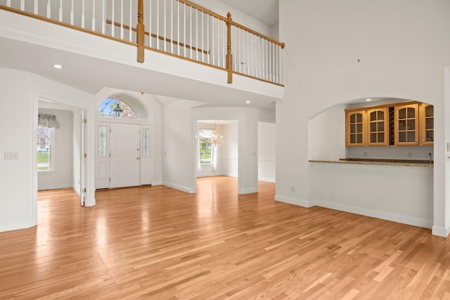 47 Cove View Dr, South Yarmouth, MA 02664 - unfurnished living room featuring light wood finished floors, a chandelier, a high ceiling, baseboards, and recessed lighting