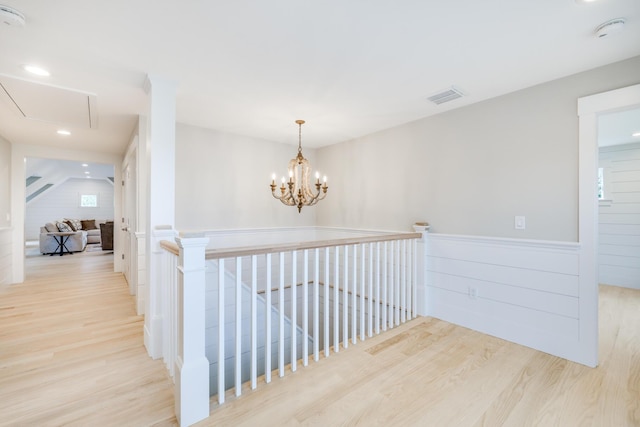 hallway featuring an inviting chandelier and light hardwood / wood-style floors