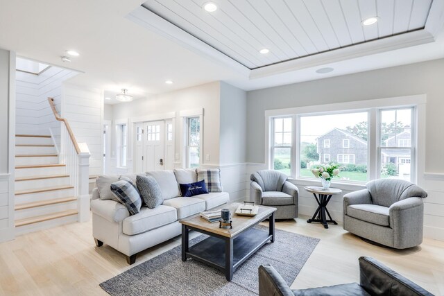 living room with light wood-type flooring, a raised ceiling, and wooden ceiling