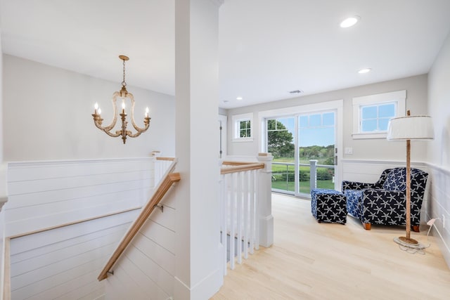 hallway with light wood-type flooring and an inviting chandelier