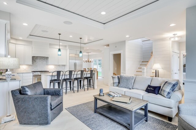 living room with a tray ceiling and a notable chandelier