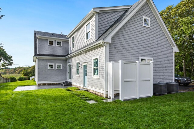 rear view of property with cooling unit and a lawn