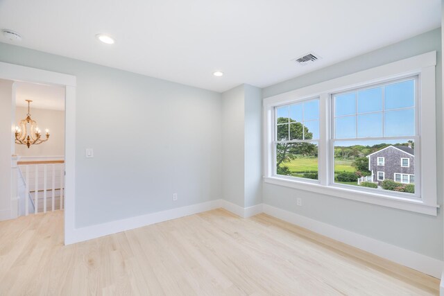 spare room featuring light hardwood / wood-style flooring and a notable chandelier