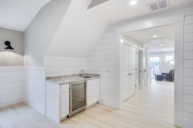 kitchen with white cabinets, light hardwood / wood-style flooring, lofted ceiling, and wine cooler