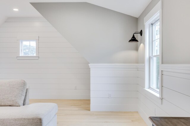 living area with light hardwood / wood-style floors, vaulted ceiling, and a healthy amount of sunlight