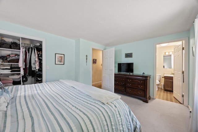 bedroom featuring light carpet, a closet, a sink, and ensuite bathroom