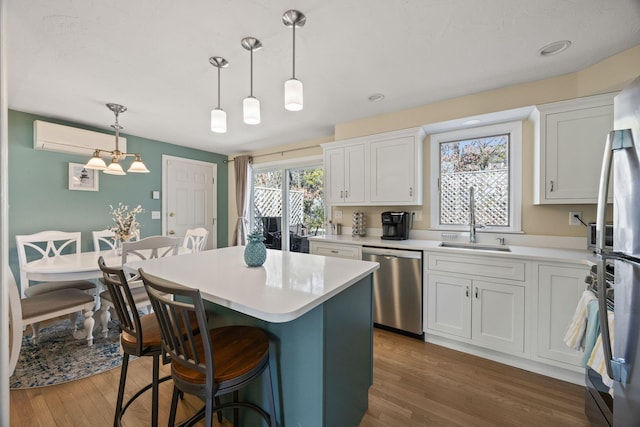 kitchen with decorative light fixtures, stainless steel appliances, light countertops, white cabinetry, and a sink