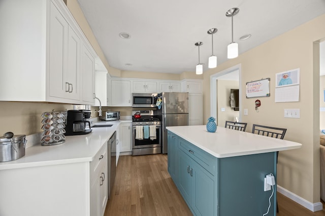 kitchen featuring stainless steel appliances, pendant lighting, light countertops, and white cabinetry