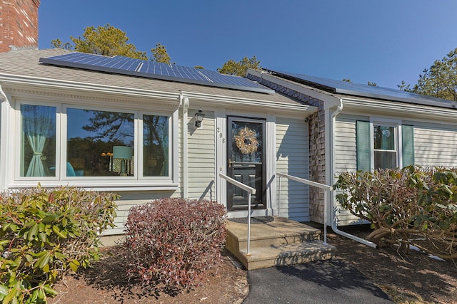 view of front of home with a shingled roof and solar panels