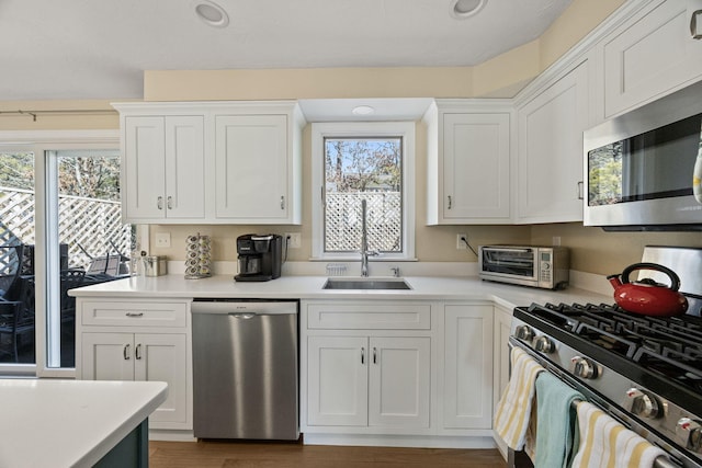 kitchen with stainless steel appliances, white cabinets, light countertops, and a sink