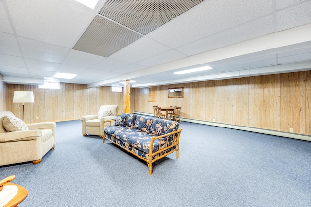 living room with a paneled ceiling, wooden walls, carpet flooring, and baseboard heating