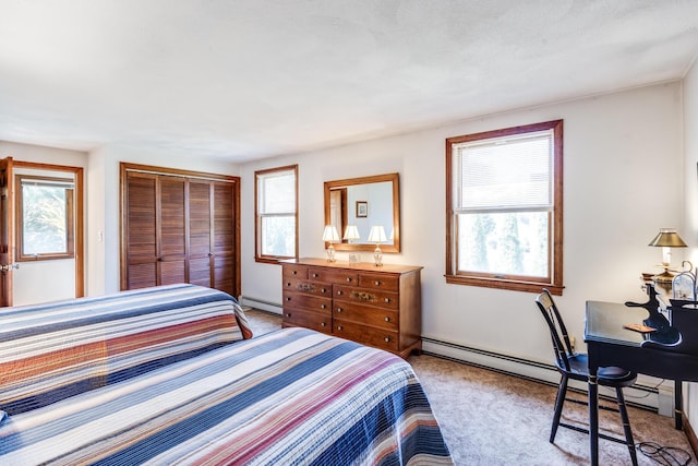 carpeted bedroom with baseboard heating, a closet, baseboards, and an office area