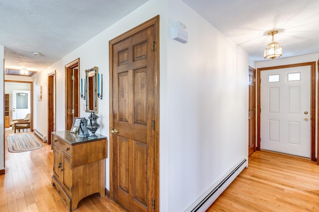 foyer entrance with a baseboard radiator, light wood-style flooring, a baseboard heating unit, and a chandelier
